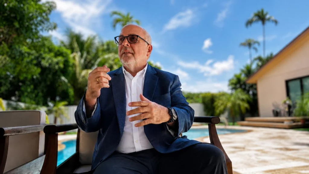 Rafael de Leon sentado durante una entrevista al aire libre junto a una piscina y una vivienda rodeada de palmeras
