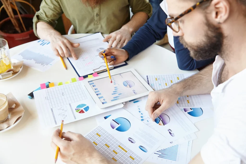 Equipo revisando gráficos, tablas y una tableta durante una reunión de análisis y planificación financiera