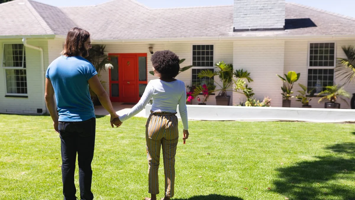 Pareja tomada de la mano frente a una casa unifamiliar con jardín en una zona residencial de Florida