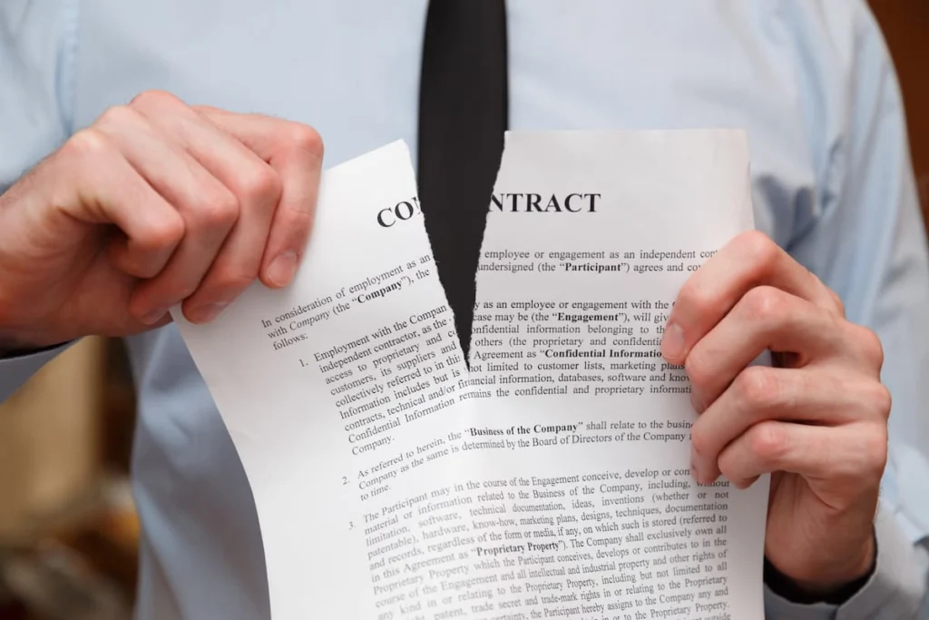 Persona rompiendo un contrato en dos partes como símbolo de cancelación o incumplimiento de un acuerdo