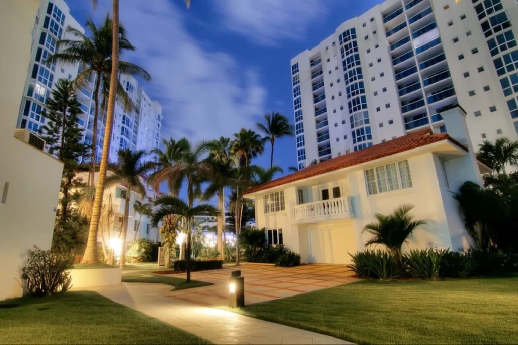 Casa unifamiliar rodeada de edificios de condominios y palmeras en un entorno residencial de Miami