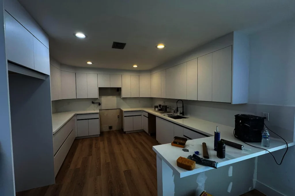 Cocina en fase final de remodelación con gabinetes instalados, encimeras nuevas y herramientas de trabajo