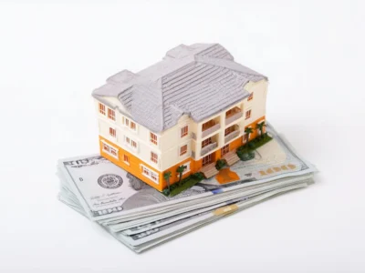 Maqueta de un edificio residencial colocada sobre un fajo de billetes de cien dólares