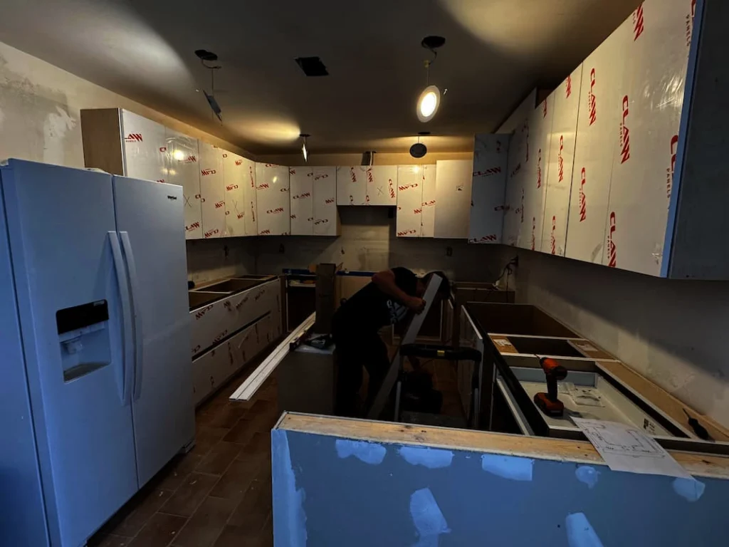 Trabajador instalando gabinetes nuevos durante la remodelación integral de una cocina