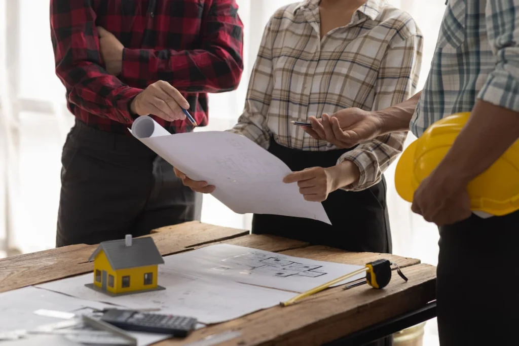 Equipo revisando planos de una vivienda durante una reunión de planificación de obra.