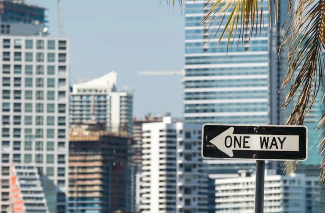 Señal de tránsito “ONE WAY” frente a edificios altos en una zona urbana