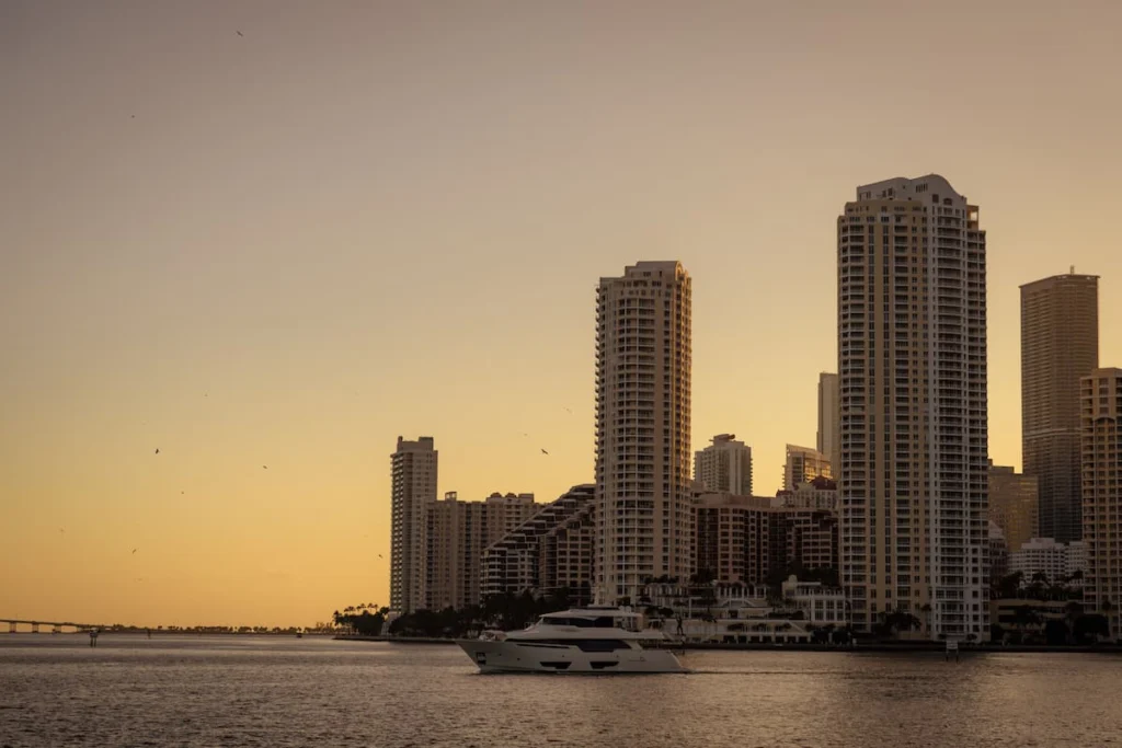Vista del skyline costero de Miami al atardecer con edificios residenciales y un yate navegando en la bahía