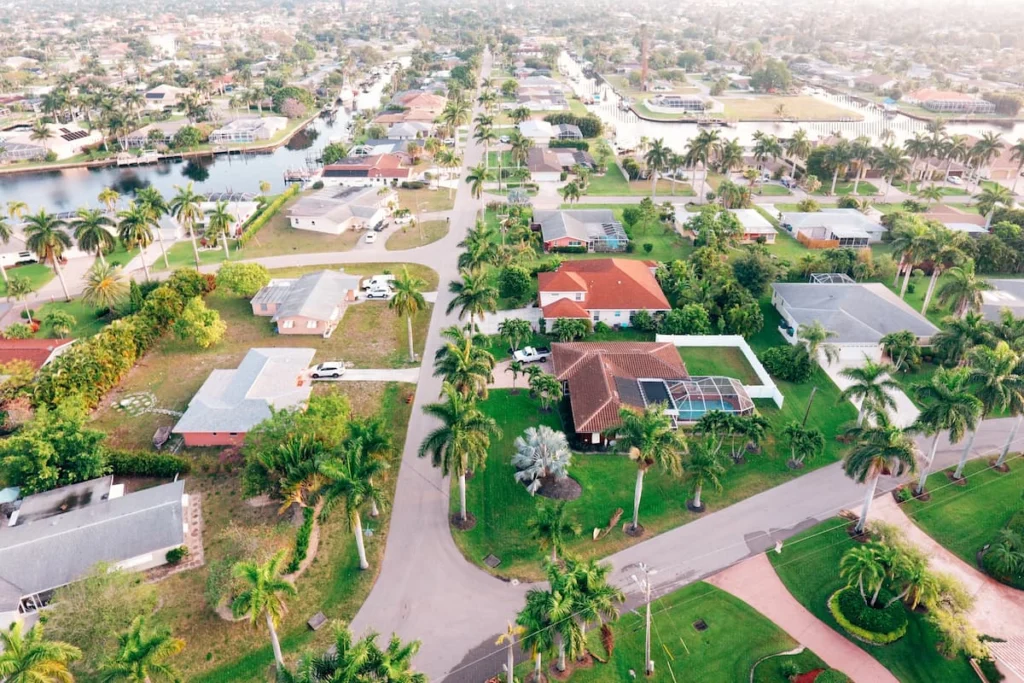 Vista aérea de un barrio residencial con casas unifamiliares, palmeras, piscinas y canales navegables