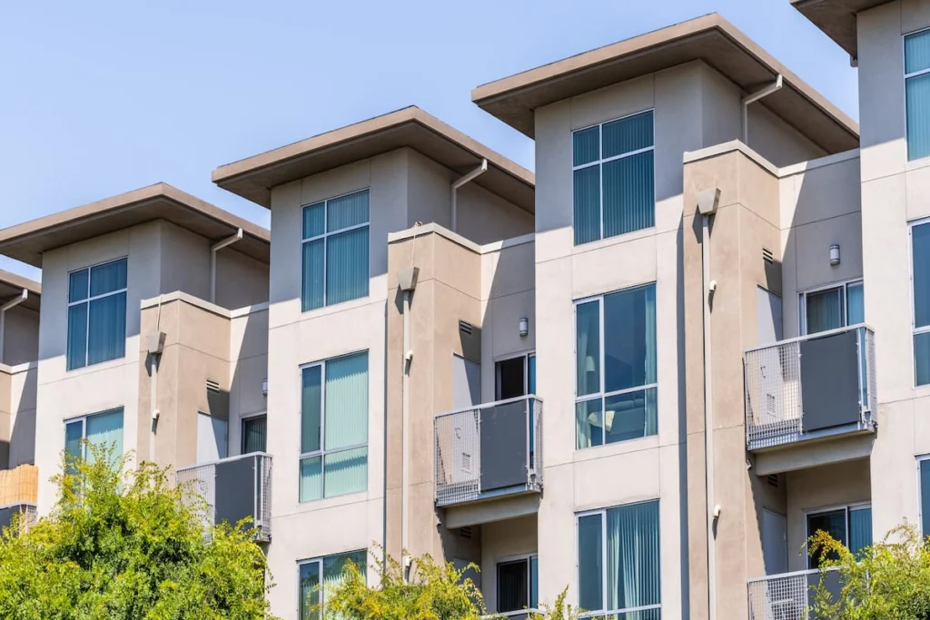 Fachada de un edificio residencial moderno de varios niveles con grandes ventanas y balcones exteriores.