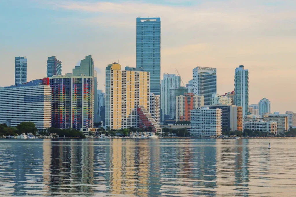 Vista del perfil urbano de Miami con edificios de gran altura frente al agua y sus reflejos sobre la bahía.